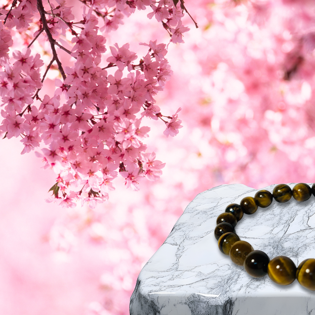 Tiger eye bracelet on a marble surface with pink cherry blossoms in the background
